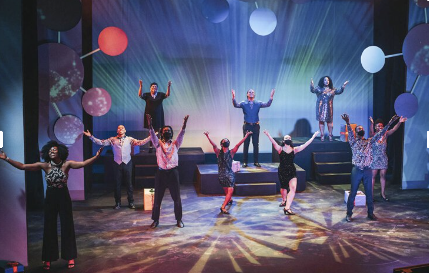 Karamu House, 10 people on stage with colorful lighting hold their arms out